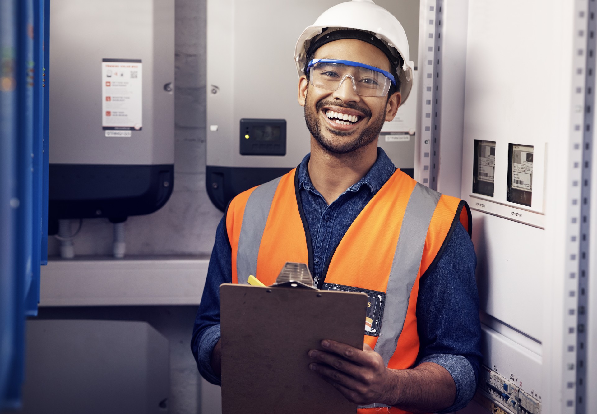 Portrait d’homme heureux, ingénieur et technicien au panneau de contrôle, inspection et planification de la maintenance sur presse-papiers. Un électricien sourit à la sous-station électrique pour l’alimentation, le système et la liste de contrôl